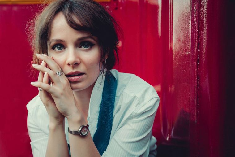 Olya framed by a red door, hands under her chin