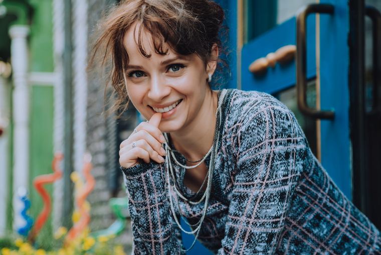 Olya smiling in a tweed jacket and pearls